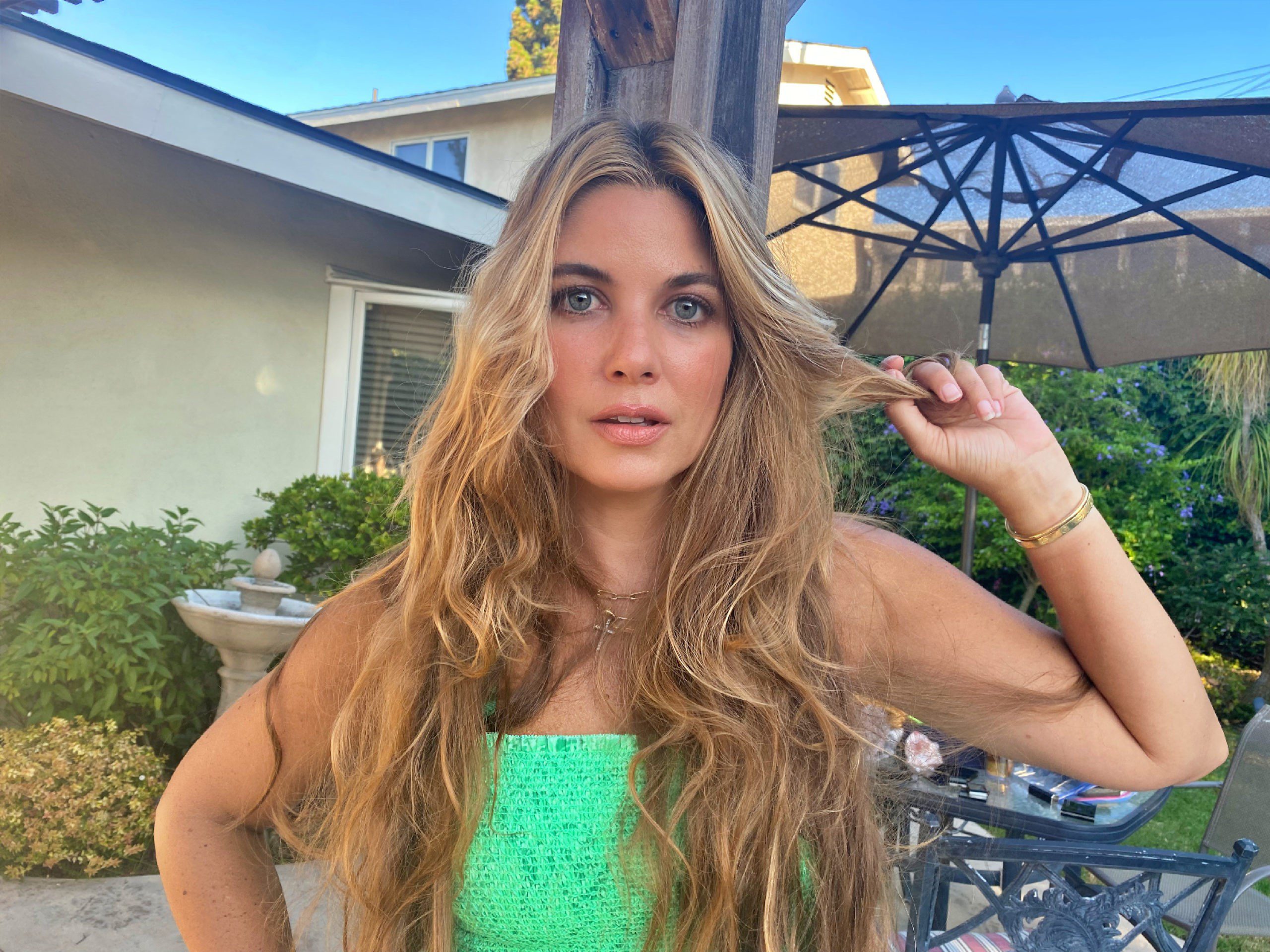 woman wearing green top and holding her hair