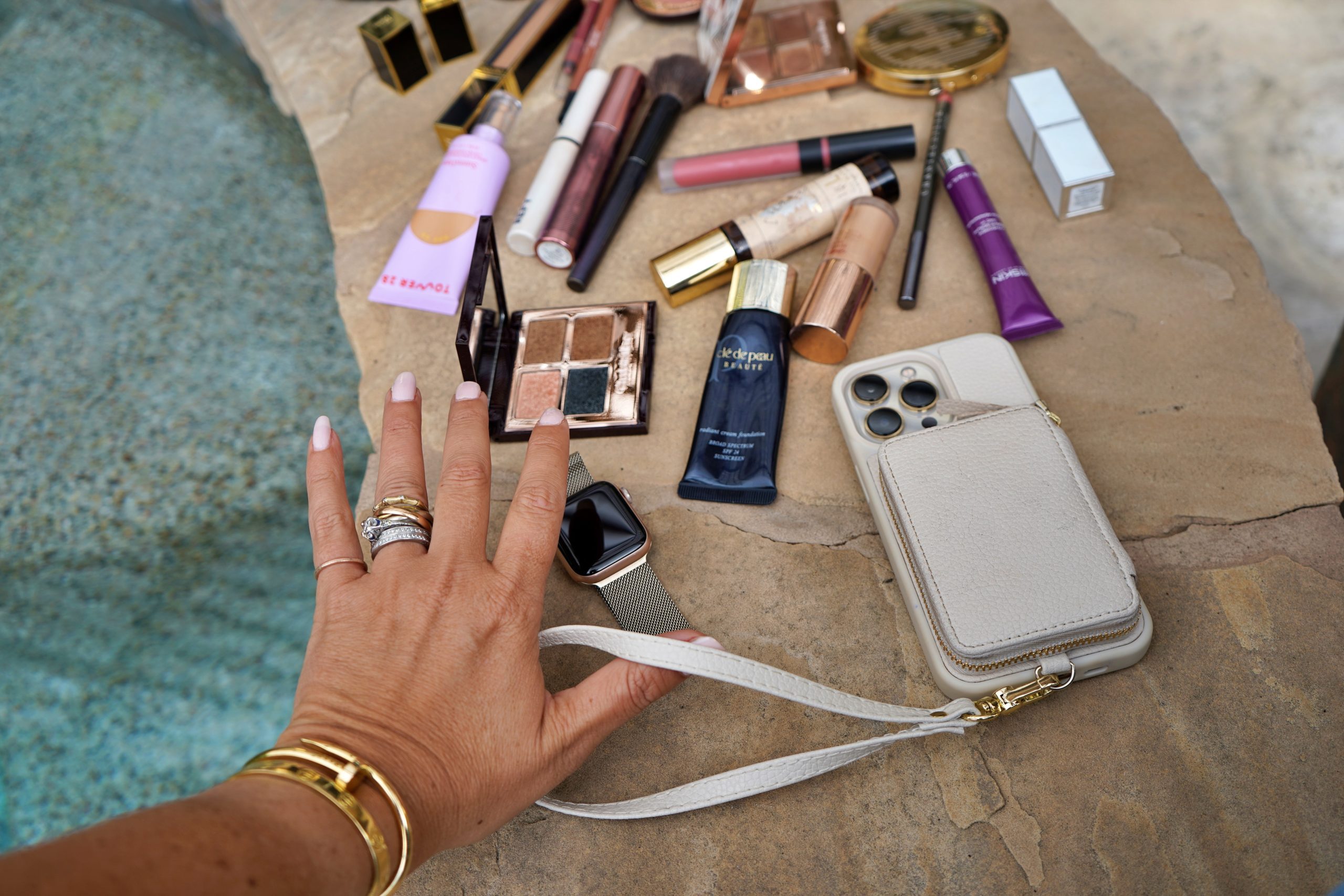 woman's hand, cellphone, and makeup sharing in whats in my bag