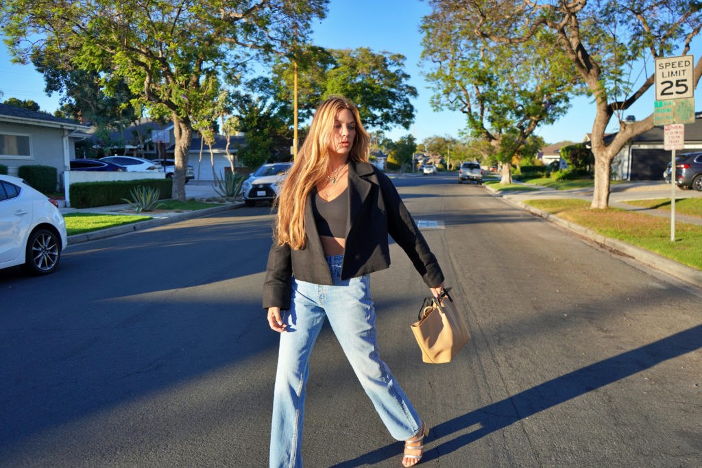 woman in black cropped top, blazer, and denim jeans