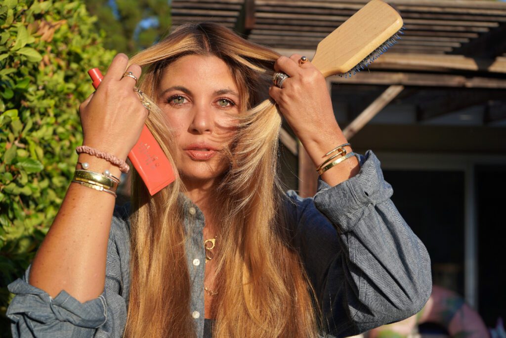 woman holding hair products to achieve healthy hair