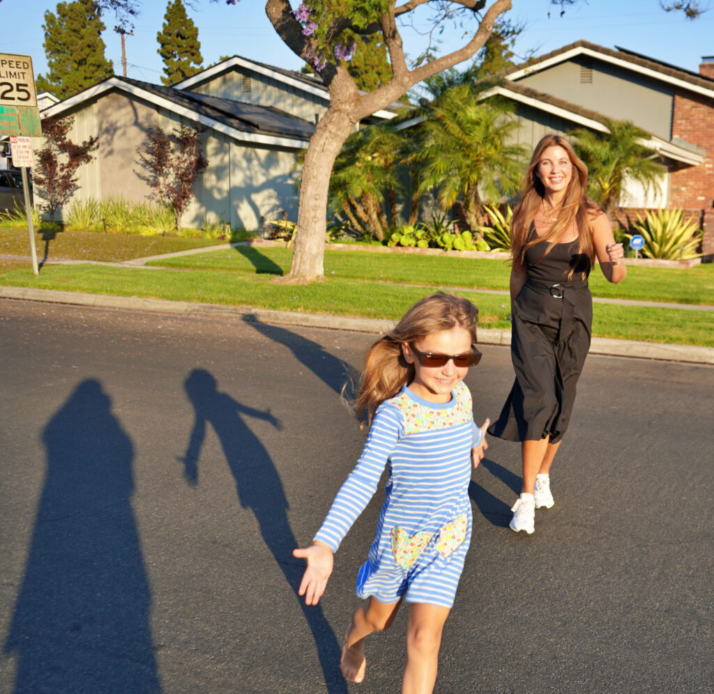 Beauty Professor Blogger Rachel Anise Wegter running with her daughter wearing their Nordstrom Anniversary Sale picks: wearing midi dress by Veronica Beard and the Autrey Reelwind Sneakers a striped while her daugher is wearing heart pocket frock (for Joey Elle) by Boden Ray-Ban rectangular sunglasses and basking under the sun