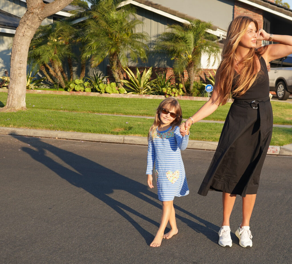 Beauty Professor Blogger Rachel Anise Wegter with their Nordstrom Anniversary Sale picks: wearing midi dress by Veronica Beard and the Autrey Reelwind Sneakers a striped while her daugher is wearing heart pocket frock (for Joey Elle) by Boden Ray-Ban rectangular sunglasses and basking under the sun